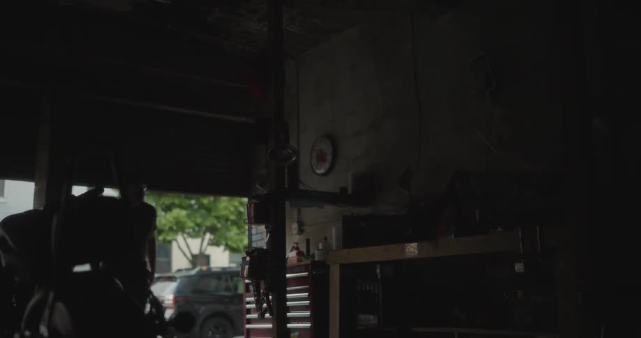 A mechanic raises the garages rolling doors and switches on the interior lights