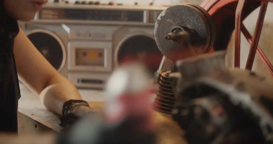 A mechanic in a workshop working on a motorcycle engine placed on a workbench