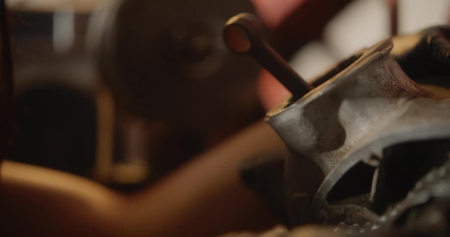 A young woman attempts to fix a gear on a motorcycle part