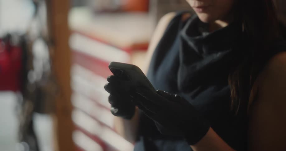 Woman with a glove focused on using an iphone