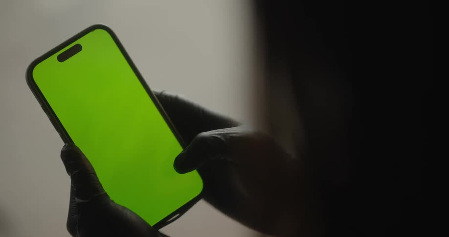 Person wearing gloves scrolls on a smartphone