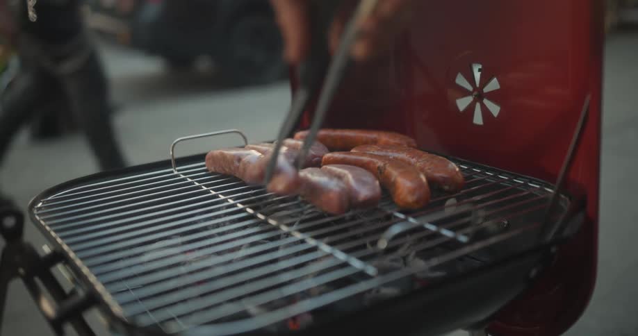 Sausages are being cooked on the grill outside