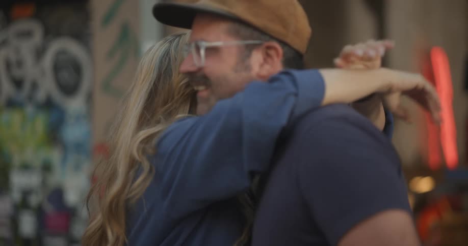 Smiling man and woman pose in front of an open garage before kissing