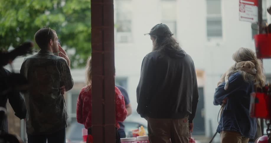 A group of friends are standing and talking at an outdoor barbecue on a summer day