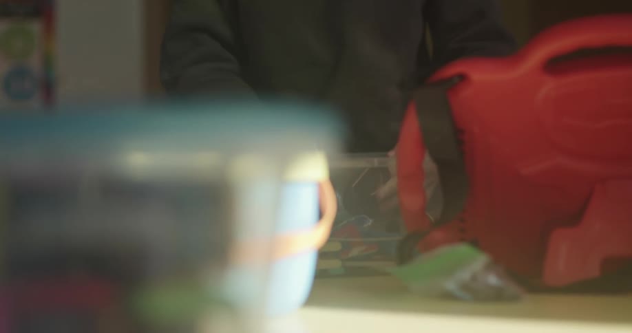 Person picking up objects inside a plastic box