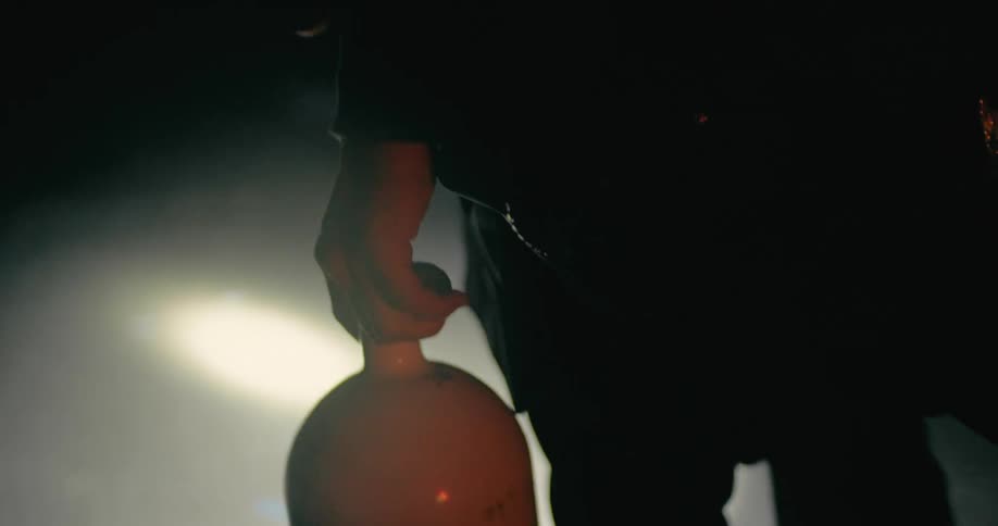 Close up of a persons hand carrying a cylinder while walking through a dark room