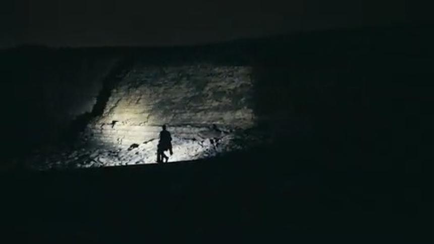 Person with a flashlight walking on rocks at night