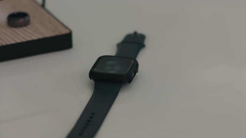 Hand picking up a smartwatch on top of a clear surface