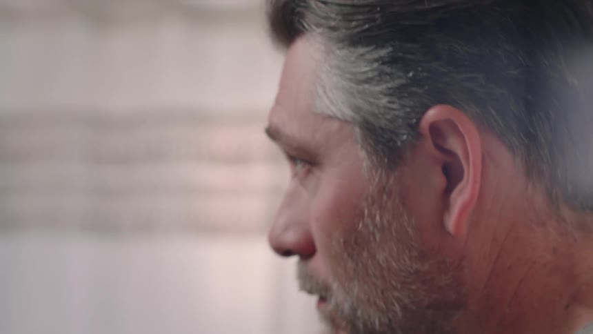 A closeup of a mans profile appearing nervous or tense he is combing his hair and rubbing his face with his hands