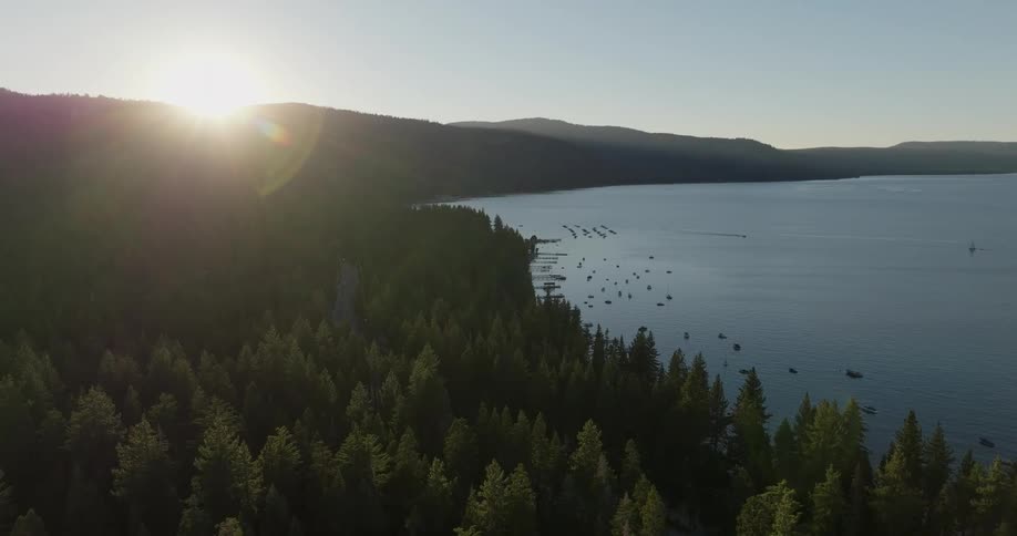 Sunset creates a silhouette effect on the trees along the lake shore