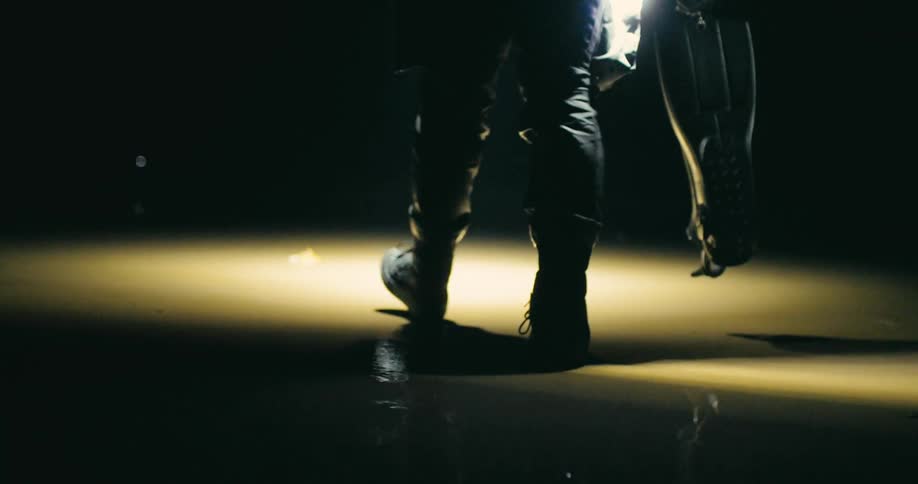 A persons legs walking on a wet sandy floor