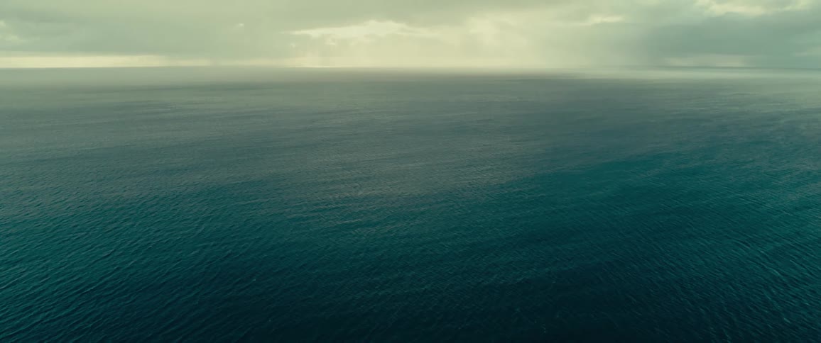 The surface of the ocean appears calm under a slightly cloudy sky