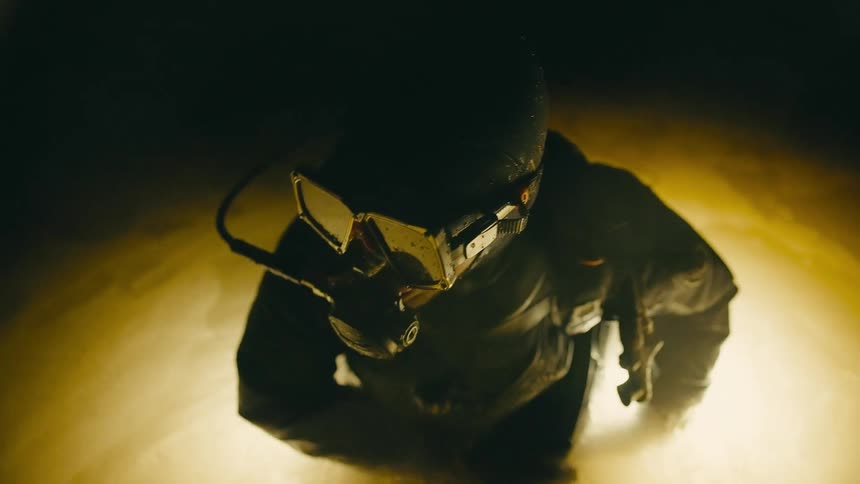 A person with diving equipment is partially underwater in a dark area and preparing to dive