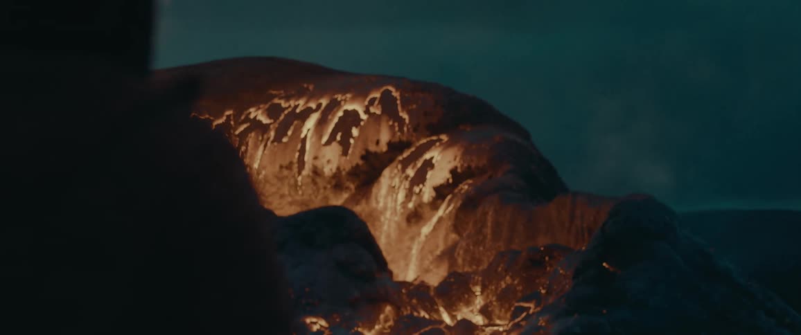 Volcano spewing volcanic magma at night with a silhouette of a person in front