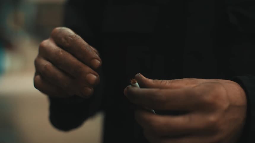 Closeup on a pair of hands holding a cigarette