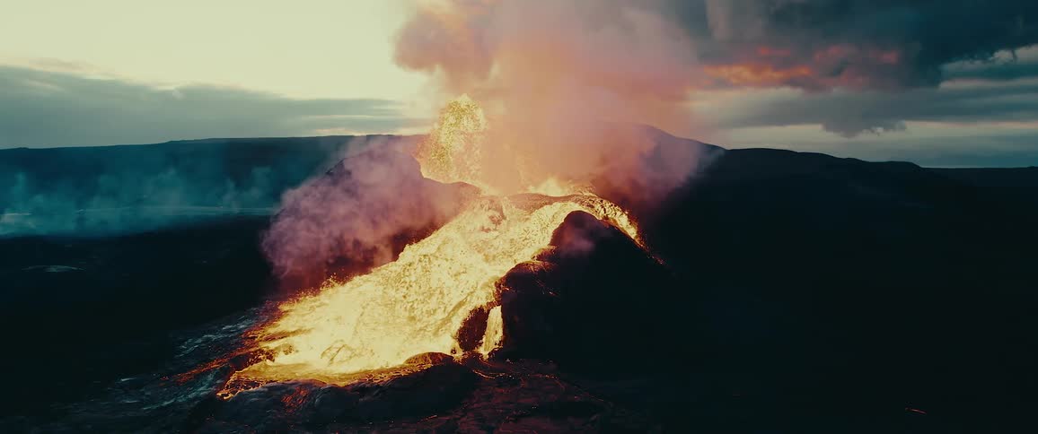 An active volcanic eruption with flowing lava and smoke against a twilight sky