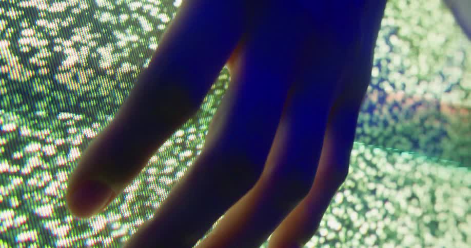 A human hand in front of a screen with several white dots flashing