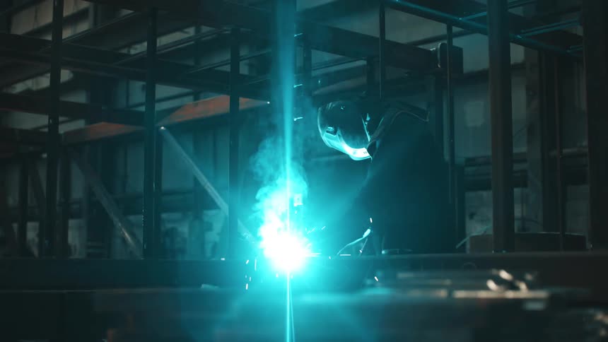 Person handling a tool that emits light and sparks while working indoors