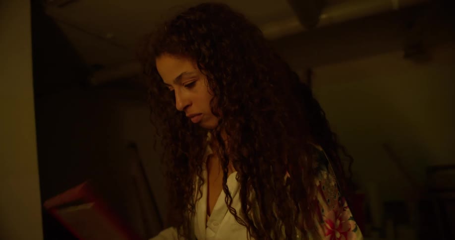 A woman with long curly hair holds a framed picture close to her chest