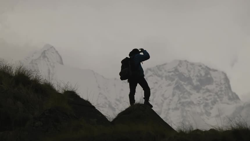 A hiker raises his arms near the mountain