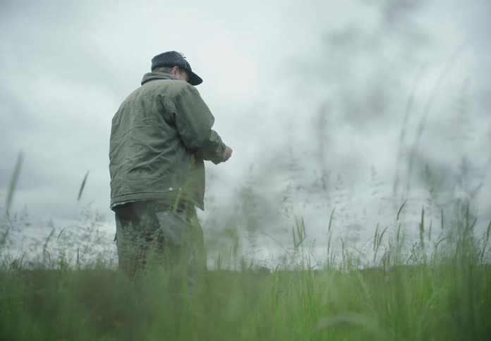 Person in a field with tall grass on a cloudy day