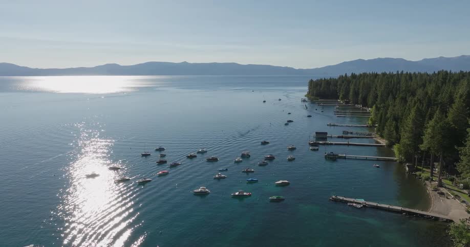 A lake with numerous boats scattered across the water surrounded by lush greenery and mountains in the background