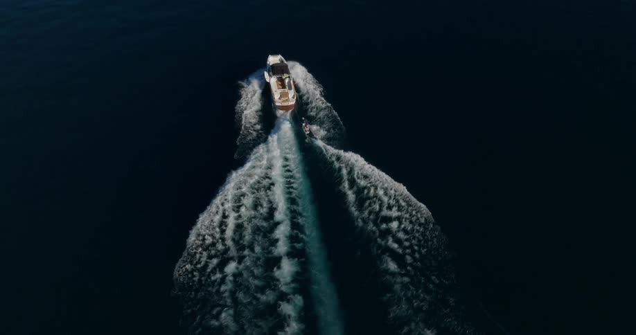 Yacht in motion and a person tied to a rope surfing
