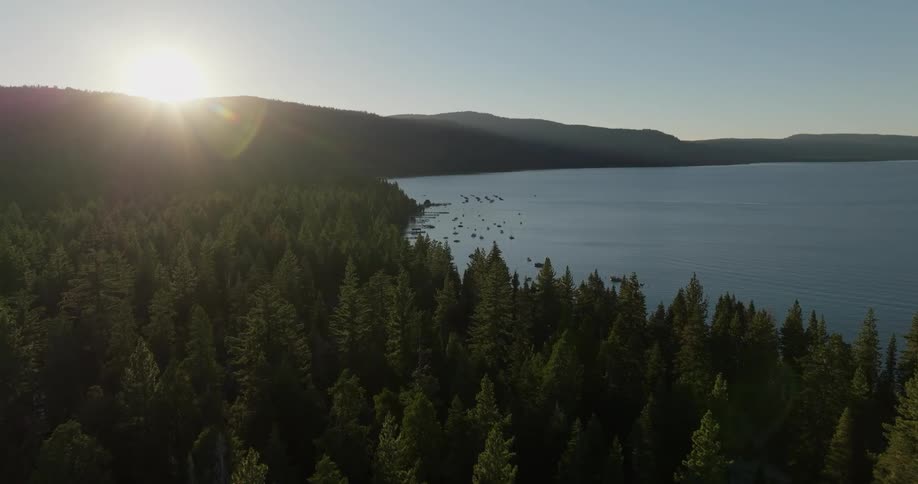 Aerial view of a sunrise or sunset over a dense forest next to a lake