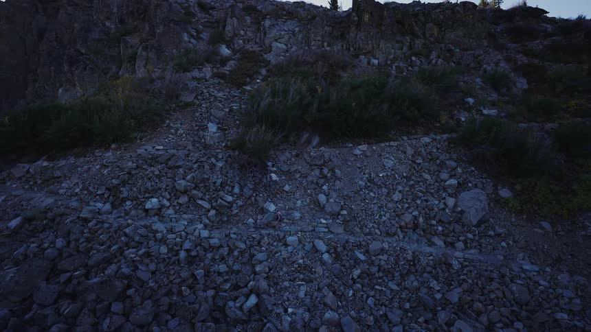An adult jogger runs up a mountain trail at dawn