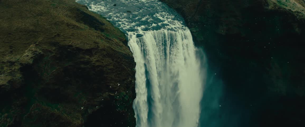 Aerial view of birds flying near a large waterfall