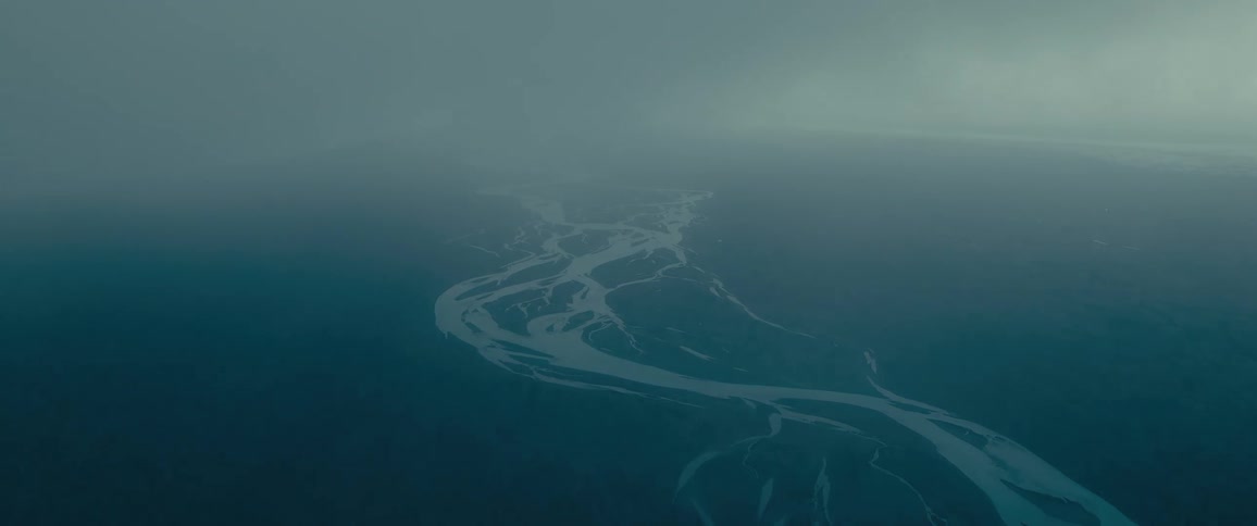An aerial view of a winding river meandering through a mistcovered landscape