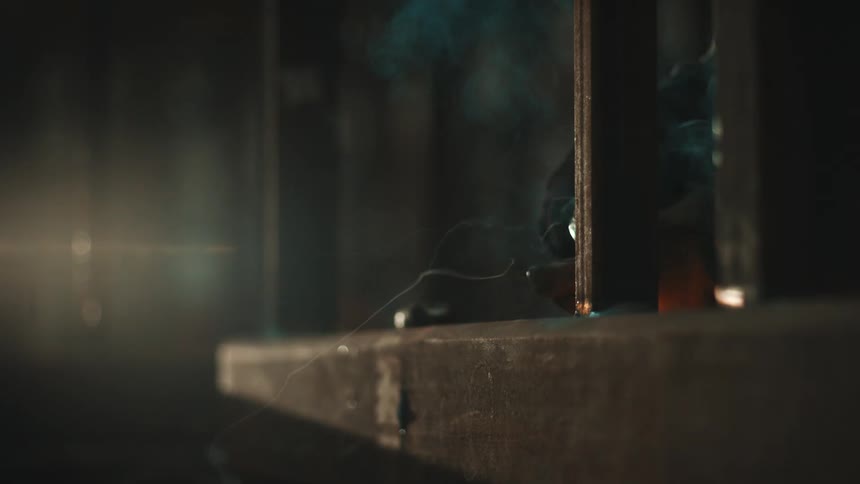 Metal welding in progress with bright blue light sparks and dark smoky environment