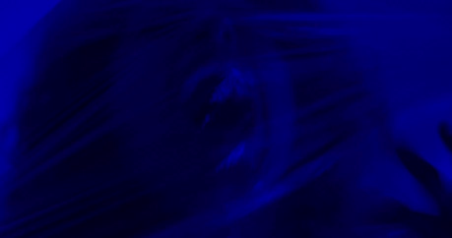 A woman her face contorted in fear struggles violently while wrapped in clear plastic sheets