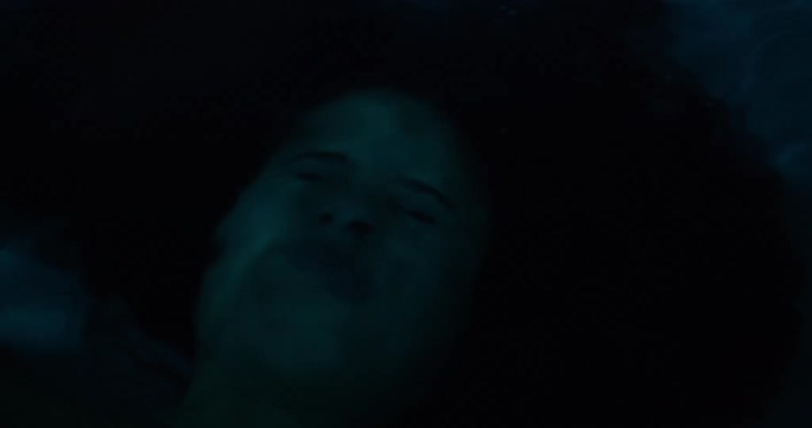 The face of a woman who has her eyes closed and she is underwater and lying down