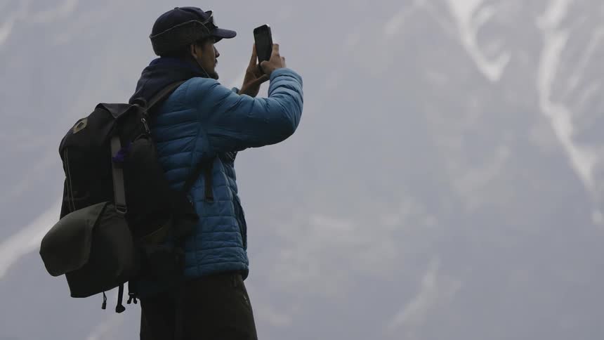 A man takes a photo of the mountain with his phone