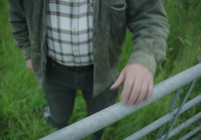 Man arm leaning on a railing in a pasture