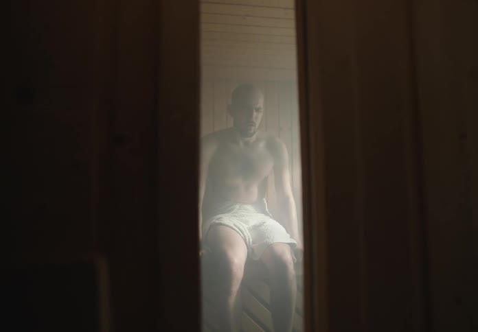 Man in towel taking deep breaths in a seated sauna