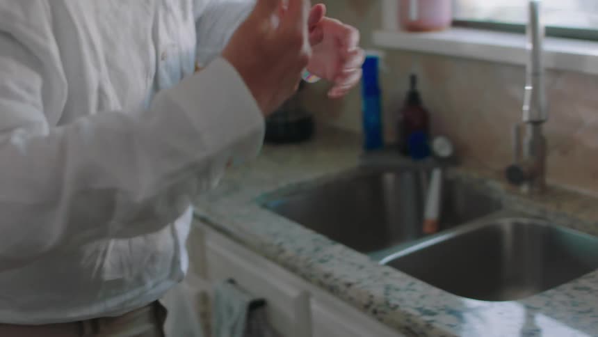 A man preparing for work sips coffee in his home kitchen accidentally he spills some on his white shirt