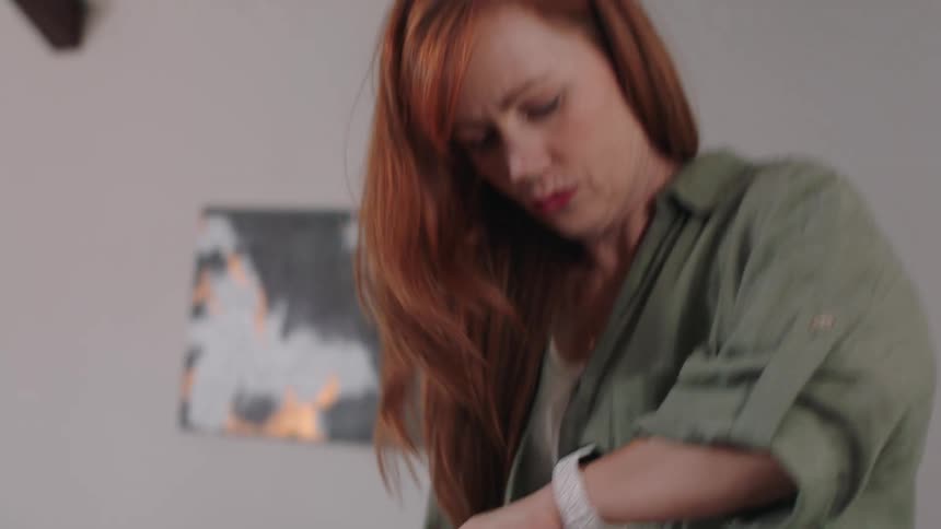 Woman putting documents inside a bag looking at her watch and leaving the house in a hurry