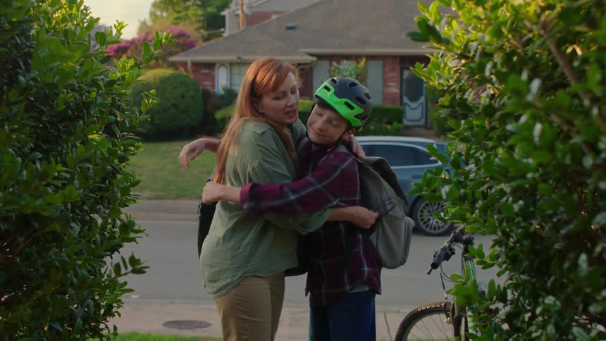 Mom and son embrace in the front yard before leaving home