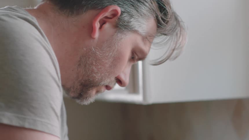 A man washes a shirt in the sink