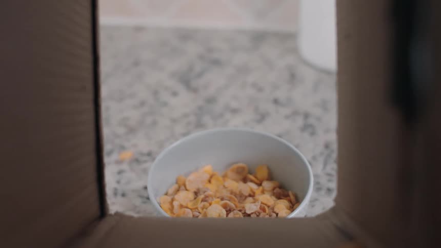 Cereal from a box being poured into a bowl
