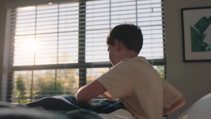 Boy stretching out of bed and standing up
