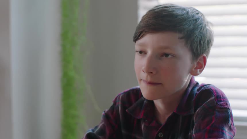 Close up of a teenage boy eating a bowl of cereal at home