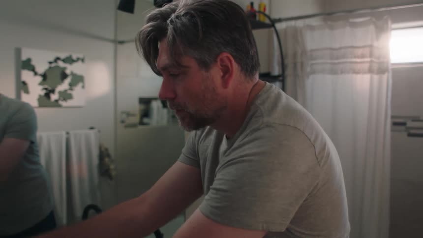 Man in bathroom putting away face towel and leaving