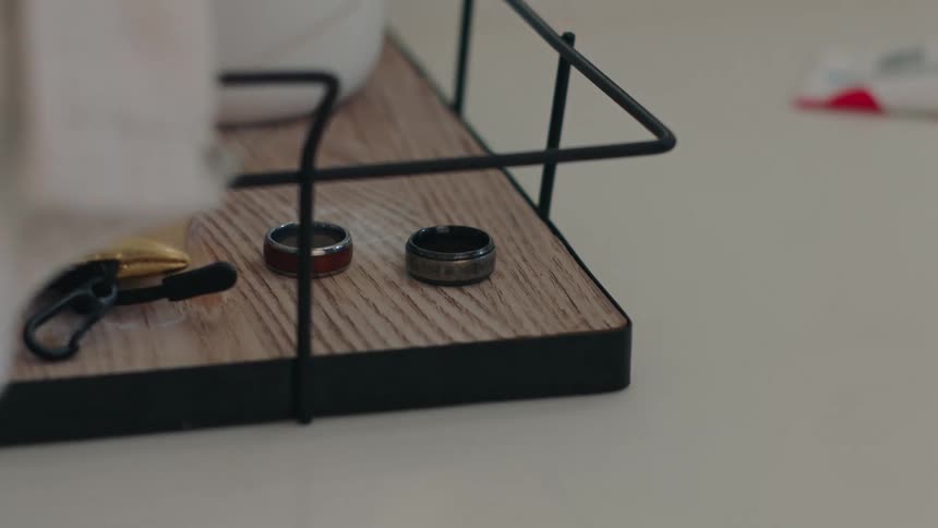 Hand picking up a ring on top of a wooden surface