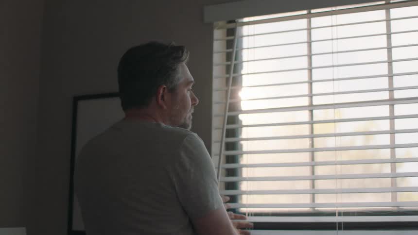 Portrait of a man waking up a person by opening the bedroom curtain
