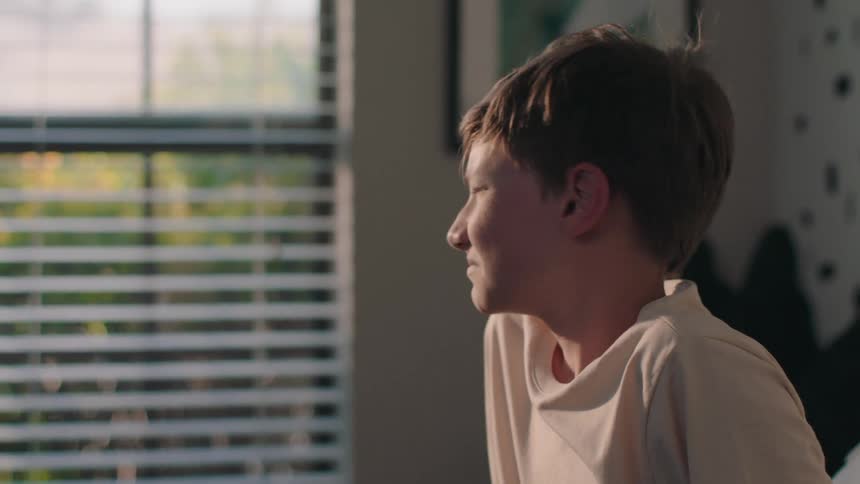A boy wakes up and gets out of bed