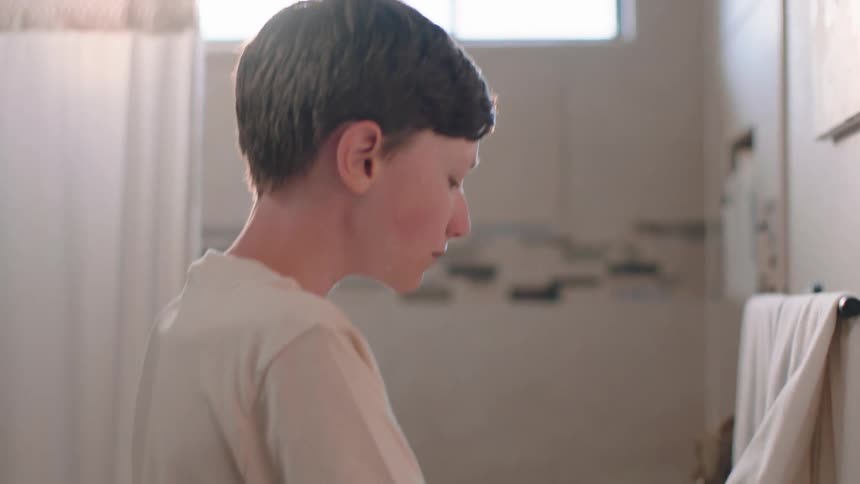 A teenage boy dries his hands with a towel in the bathroom after washing them