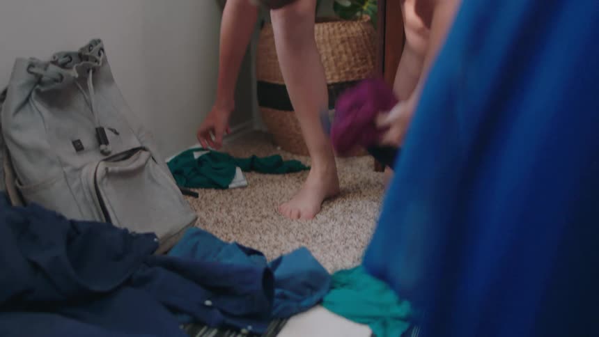 Boy looking for clothes that are thrown on the floor